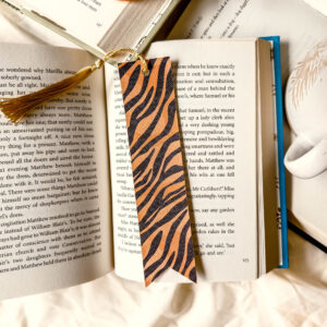 Handmade faux leather bookmark with tiger print and black tassel on white background.